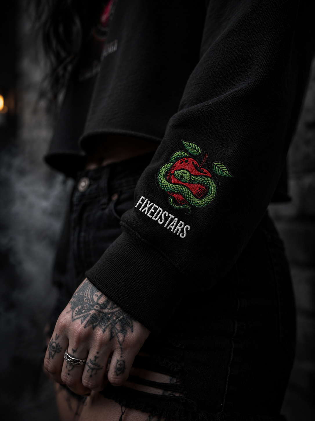 Black sweatshirt with 'FIXEDSTARS' logo on sleeve, worn by a person with tattoos.