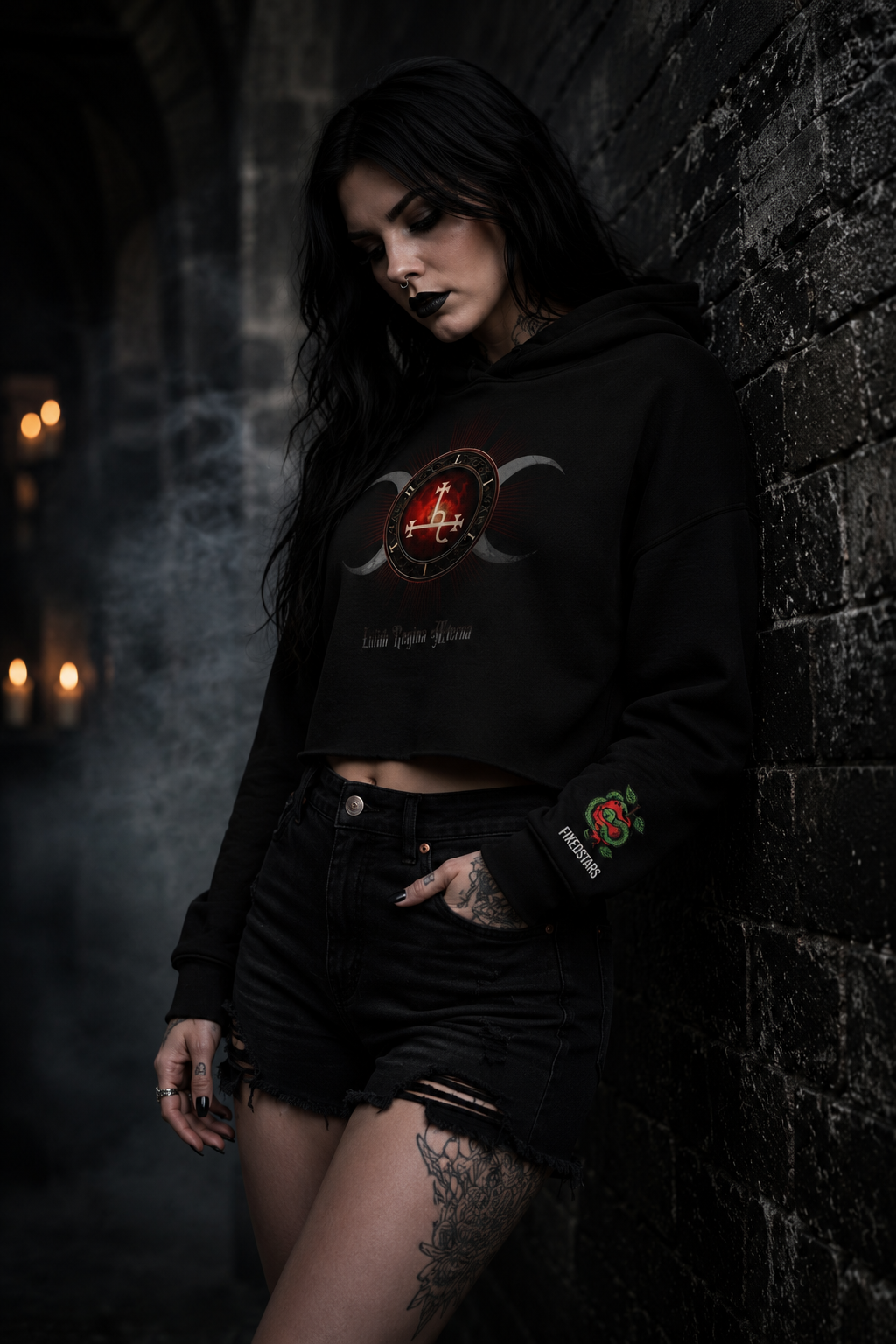 Person wearing a black hoodie with a red and gold design, standing against a dark stone wall.