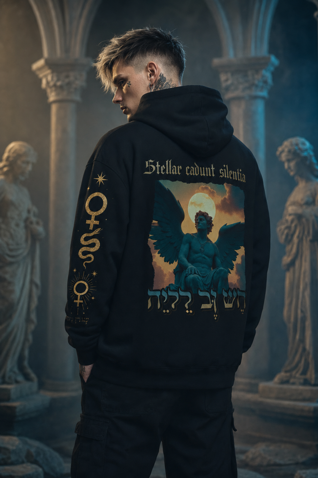 Person wearing a black hoodie with angel design and text in an ancient setting