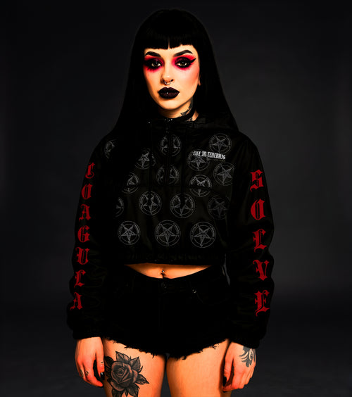 Person wearing a black windbreaker with red and white text and designs on a dark background