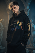 Person wearing a black hoodie with visible branding in an artistic, possibly gothic setting.